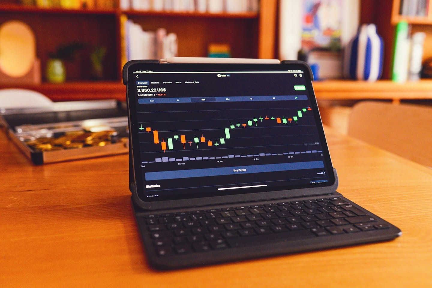 Tablet displaying cryptocurrency chart on a wooden desk.